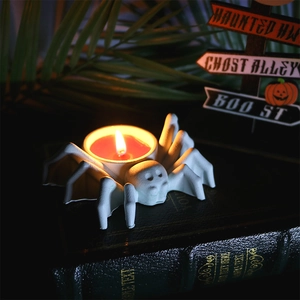 Spider shaped tea light holder for Halloween decor with a burning candle on a book