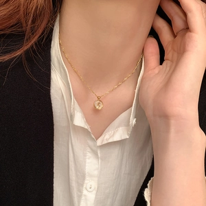 Detailed close-up of a golden French tulip necklace on model with water wave chain