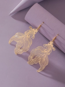 Detail of golden hollow koi fish earrings showing intricate scales on purple background
