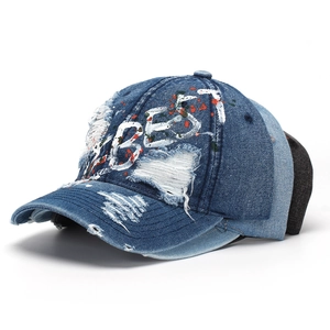 Close-up of distressed denim baseball caps with BEST embroidery and paint splatters