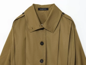 Detail of olive green trench coat featuring shoulder epaulettes and INDEFEIR brand label