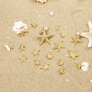 Golden starfish, turtle and seashell pendants for DIY jewelry on beach sand background