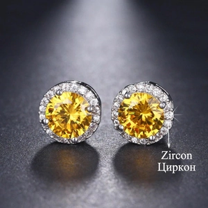 Macro shot of silver stud earrings with a yellow round zircon center and white halo gems