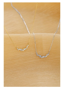 Macro detail of gold and silver necklaces with sparkling cubic zirconia on silk fabric