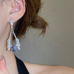 Detail of elegant silver drop earrings with blue rectangular zircon and pavé stones
