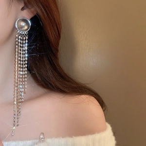 Long tassel earrings with grey pearl disc and shimmering diamond chains on a model