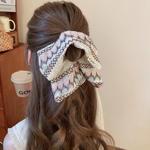 Détail d'une grande pince à cheveux nœud en tricot crème avec des motifs en zigzag brodés