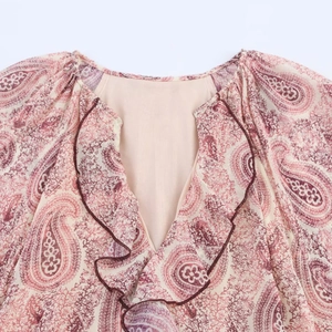Close-up of V-neckline with ruffled edges and paisley print on pink chiffon fabric