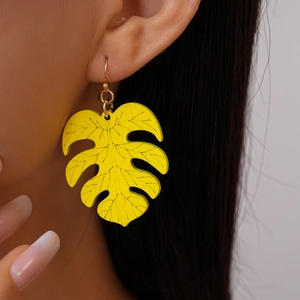 Detail of vibrant yellow Monstera leaf earrings with realistic black vein textures
