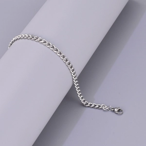 Minimalist silver stainless steel Cuban link bracelet for men and women on a display stand