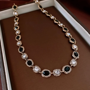 Close-up of vintage gold necklace with black oval gemstones and sparkling zircon detail