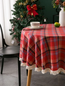 Close-up of red plaid round tablecloth with white fringe tassels and festive weave texture