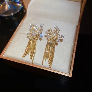 Elegant gold-tone fringe earrings with firework cluster pearls and crystals on a box