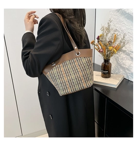 Detail of vintage plaid bucket bag with brown leather trim and metal eyelet accents