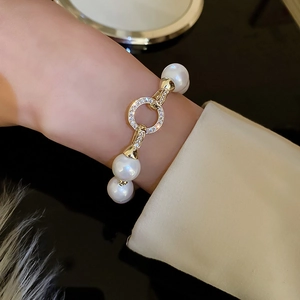 Detail of gold plated pearl bracelet with zircon clasp worn on model wrist