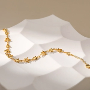 18K gold-plated star charm bracelet with hollow and solid stars on a textured background