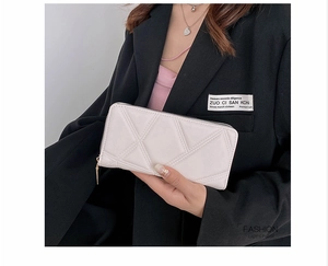Detail of beige quilted PU leather wallet with geometric stitching and gold zipper closure