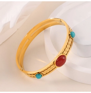 Macro shot of gold vintage cuff with red gemstone and turquoise floral relief details