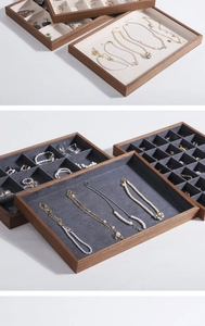 Detail of walnut wood jewelry trays with beige and dark grey velvet lining and dividers