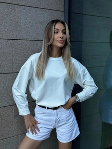 Vista di una modella all'aperto con felpa bianca a maniche lunghe e pantaloncini bianchi