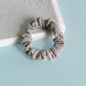 Détail d'un chouchou en velours côtelé gris clair avec texture élastique plissée