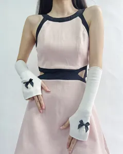 Detail of white rib-knit arm warmers featuring black satin bows and pearl charms