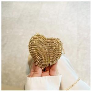 Detail of a mini heart-shaped evening bag with gold rhinestones and elegant chain strap