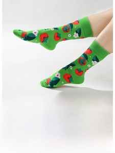 Détail de chaussettes en coton vert avec motifs de fruits rouges et fleurs blanches