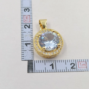 Macro view of a gold-plated round pendant with zircon stones showing precise dimensions