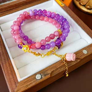 Detail of pink and purple beaded bracelet with gold flower charms and a rose pendant