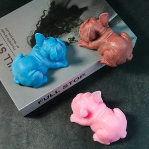 Bulldog silicone candle molds in blue, pink, and brown on a textured table surface