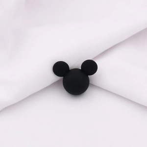 Close-up of matte black Mickey-shaped ABS beads on white textured fabric for DIY jewelry