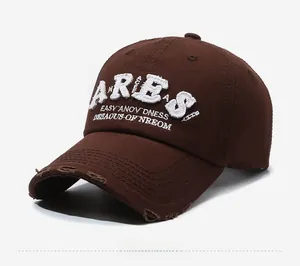 Detailed close-up of dark brown baseball cap featuring white ARIES embroidery and distressed brim