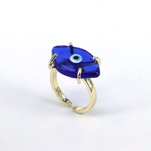 Detail of golden adjustable ring featuring a blue glass evil eye charm on white background