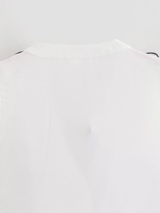 Detail of the white top neckline showing sewing craftsmanship and woven fabric texture