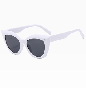 Detail view of white cat-eye sunglasses featuring three silver metal studs on the frame