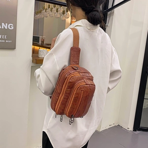 Sac de poitrine marron à motif crocodile avec large bandoulière porté par un mannequin