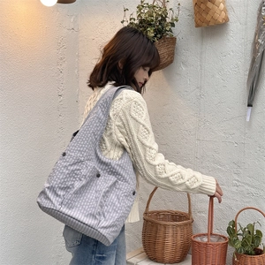 Detail of grey plaid tote bag with external pockets worn with cozy knit sweater