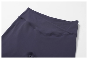 Detail of high-waisted V-shaped crossover waistband on purple yoga flare pants