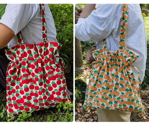 Detalle de bolsos de lona con cordón y estampados coloridos de cerezas y naranjas