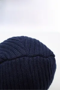 Detailed close-up of dark blue knit winter hat showing thick warm texture and stitching