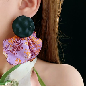 Detail of purple embroidery and black resin stud earring on a profile model view