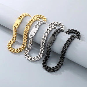 Detailed close-up of Cuban link chains in gold, silver, and black on a cylinder display