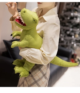 Detail of green plush dinosaur toy with textured fabric and soft white teeth on a sofa
