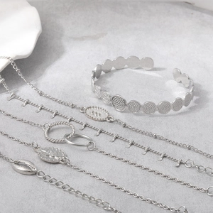 Close-up of silver-tone bracelets set with moon and leaf charms on stone surface