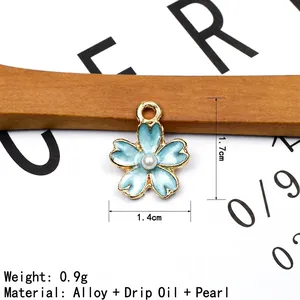 Macro shot of light blue enamel cherry blossom charm with pearl and size details