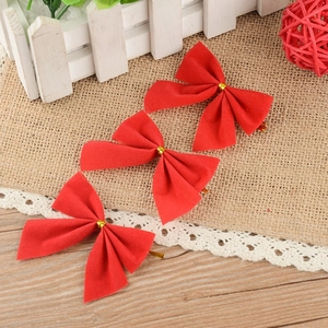 Three red velvet Christmas bows with gold ties on rustic wooden and burlap background