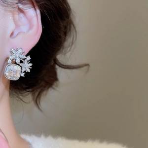 Détail de boucles d'oreilles fleur argentées avec cristaux de zircon carrés pour le style