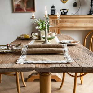 Detail of jute table runner with white lace trim on a rustic wooden dining table