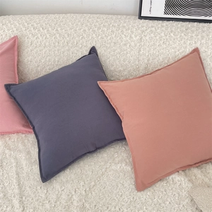 Detail of soft solid color pillow covers in blue and pink on white faux fur sofa